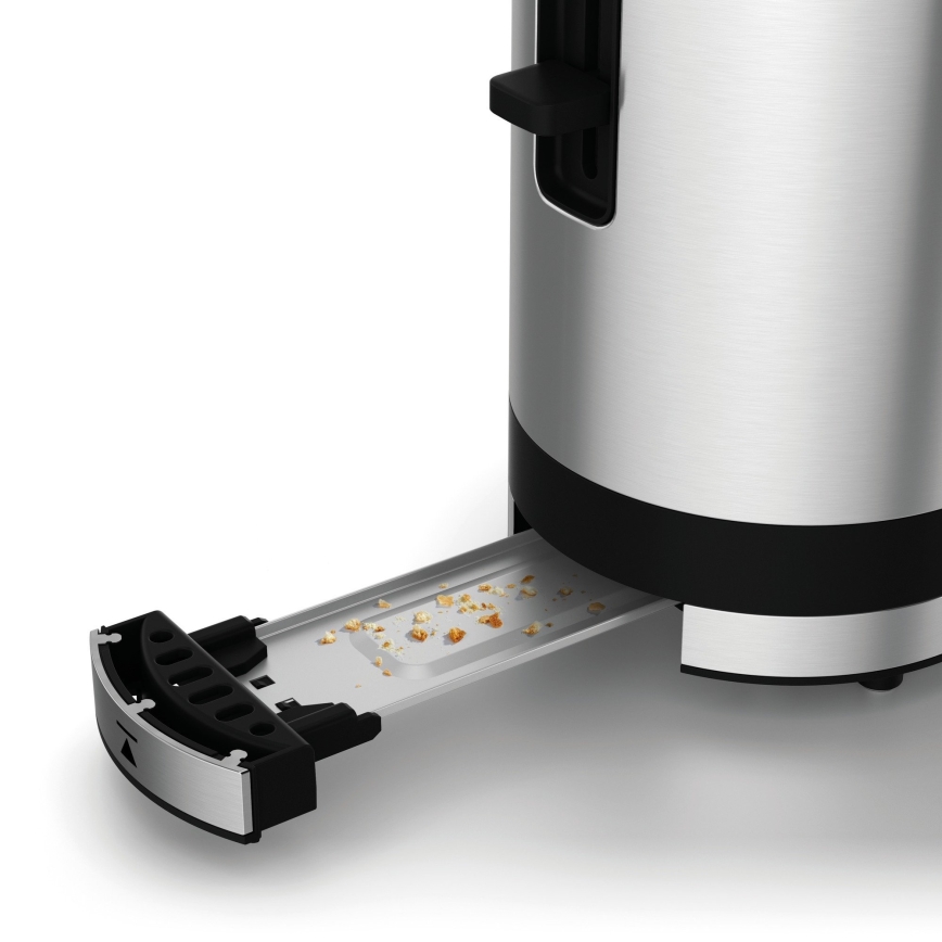 Strieborný toastovač s čiernym lemom má vysunutú zásuvku na omrvinky, na ktorej sa nachádzajú drobky. Zásuvka je čiastočne vytiahnutá z tela toastovača.