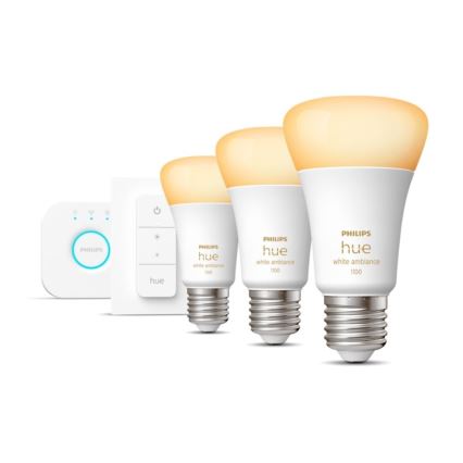 Tri žiarovky Philips Hue s teplým bielym svetlom, rôznych veľkostí, sú umiestnené vedľa stmievača a ovládača. Žiarovky sú označené PHILIPS hue white ambiance 1100 a 100.
