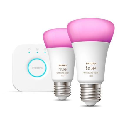 Dve inteligentné žiarovky Philips Hue s ružovým svetlom a bielym telom, s nápisom „PHILIPS hue white and color 1100“, sú umiestnené vedľa malého bieleho ovládača s nápisom „PHILIPS“.