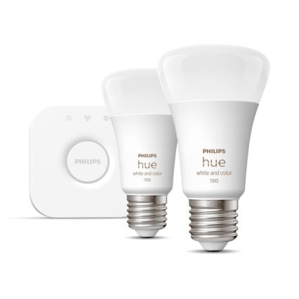 Dve inteligentné žiarovky Philips Hue white and color 1100 s čírym sklom a šroubovacím závitom sú umiestnené vedľa štvorcového ovládača Philips.