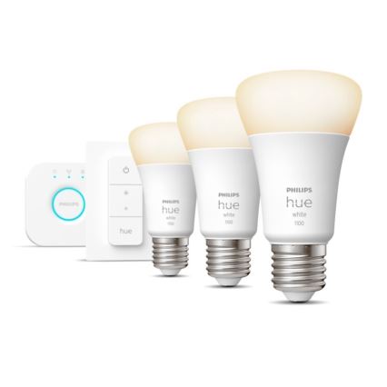 Tri žiarovky Philips Hue White 1100 svietia na bielom pozadí. Vedľa nich sa nachádza diaľkový ovládač a stmievač.