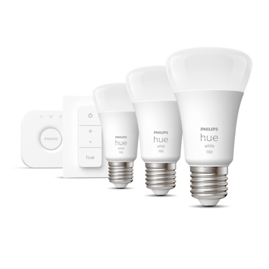 Tri LED žiarovky Philips Hue white 1100 rôznych veľkostí sú umiestnené na bielom podklade popri ovládači Philips Hue.