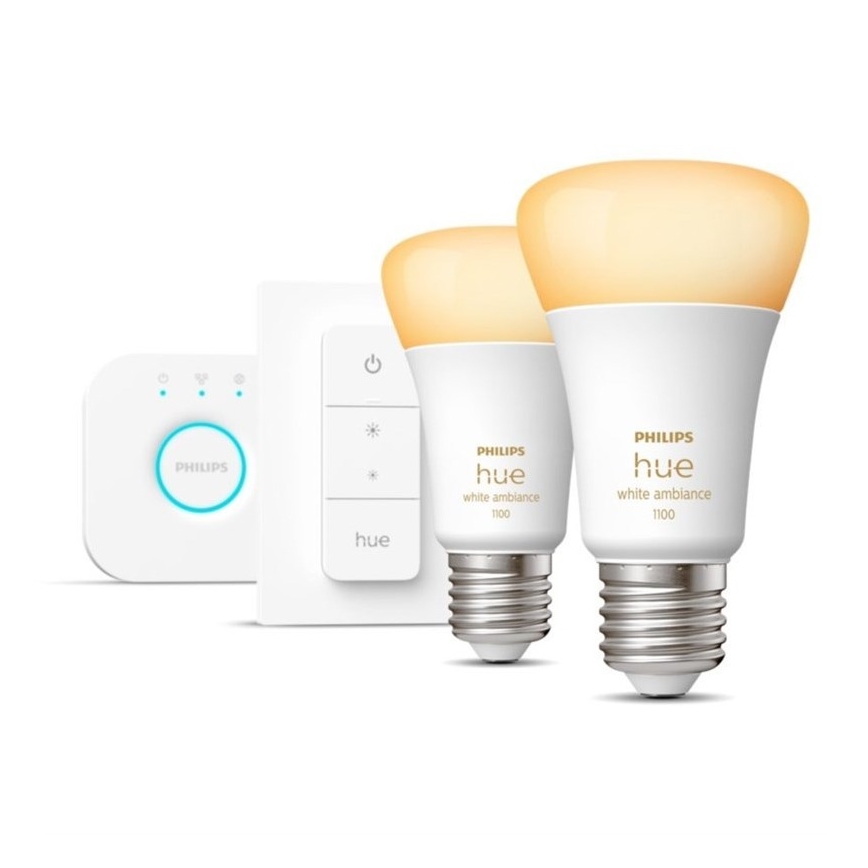 Dve inteligentné žiarovky Philips Hue white ambiance 1100 svietia slabou žltou farbou. Sú umiestnené vedľa diaľkového ovládača a stmievača.