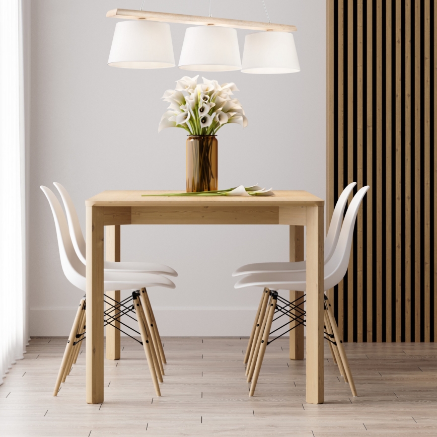 Drevený jedálenský stôl s tromi bielymi plastovými stoličkami stojí v miestnosti s drevenou stenou. Na stole je váza s bielymi kvetmi.