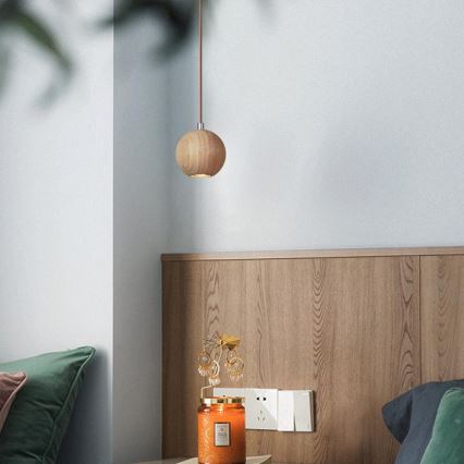 Drevené guľové svietidlo visí zo stropu. Nachádza sa v spálni pri posteli s dreveným čelom, na nočnom stolíku je sviečka a stojan na náušnice.