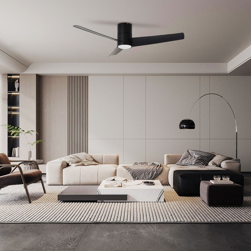 Čierny stropný ventilátor s tromi lopatkami sa otáča v moderne zariadenej obývacej izbe s bielym gaučom, konferenčným stolíkom a kobercom.