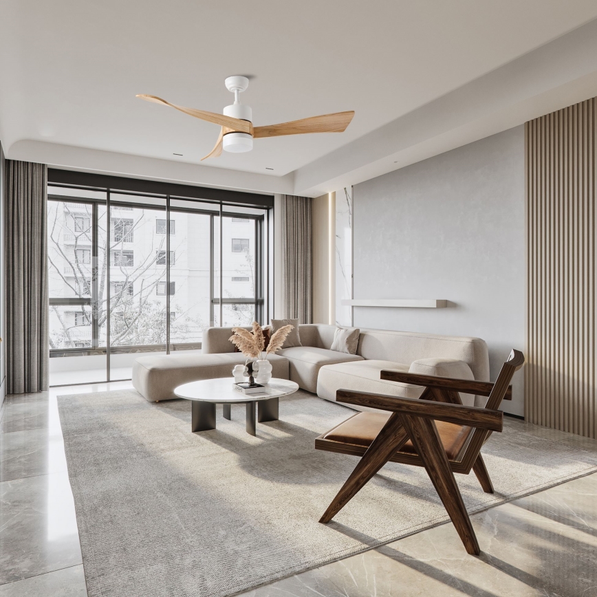 Drevený stropný ventilátor s bielym puzdrom rotuje v moderne zariadenej obývacej izbe s rozsiahlym oknom a svetlou sedacou súpravou. Izba obsahuje kožený kreslo a oválny konferenčný stolík.