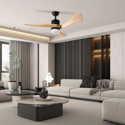 Drevený stropný ventilátor s čiernym krytom a integrovaným svetlom sa otáča v modernej obývacej izbe s bielou sedačkou a nízkym konferenčným stolíkom.