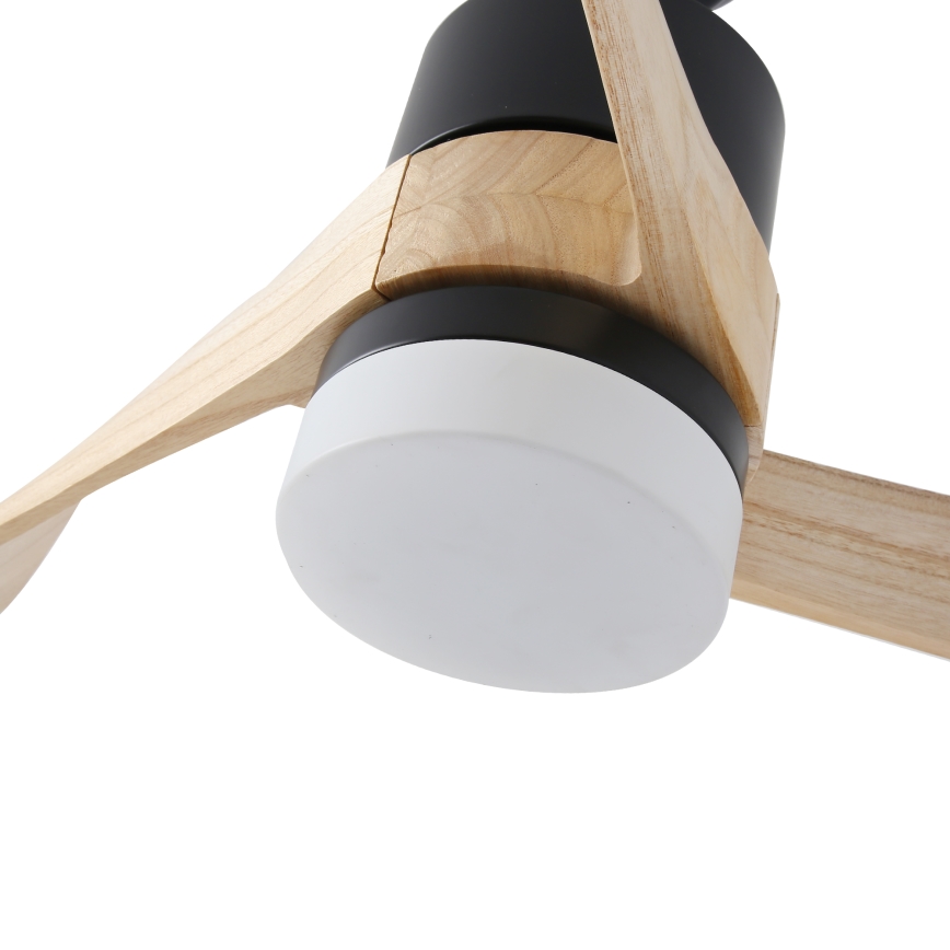 Drevený stropný ventilátor s čiernymi kovovými časťami a bielym difúzorom svetla sa nachádza v bielom pozadí. Ventilátor je čiastočne viditeľný, zameraný je na jeho detail.