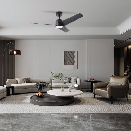 Čierny stropný ventilátor s troma lopatkami rotuje v moderne zariadenej obývacej izbe s pohovkou, kreslom a nízkym konferenčným stolíkom.