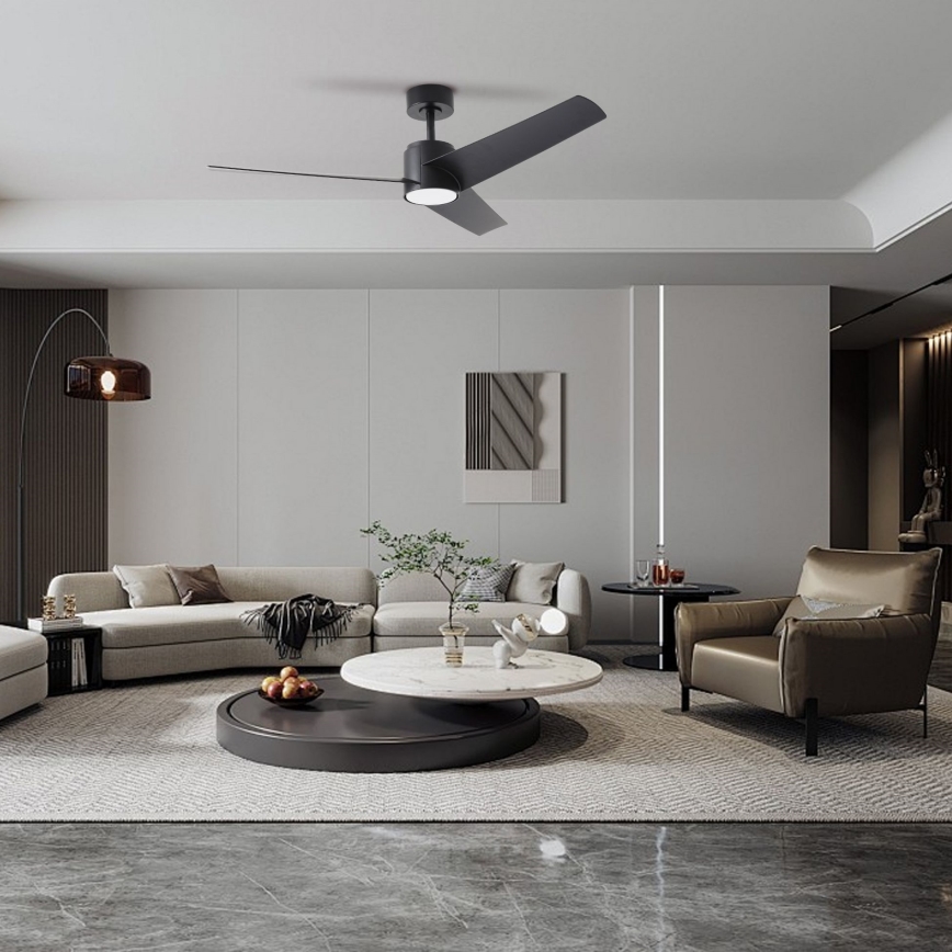 Čierny stropný ventilátor s troma lopatkami rotuje v moderne zariadenej obývacej izbe s pohovkou, kreslom a nízkym konferenčným stolíkom.