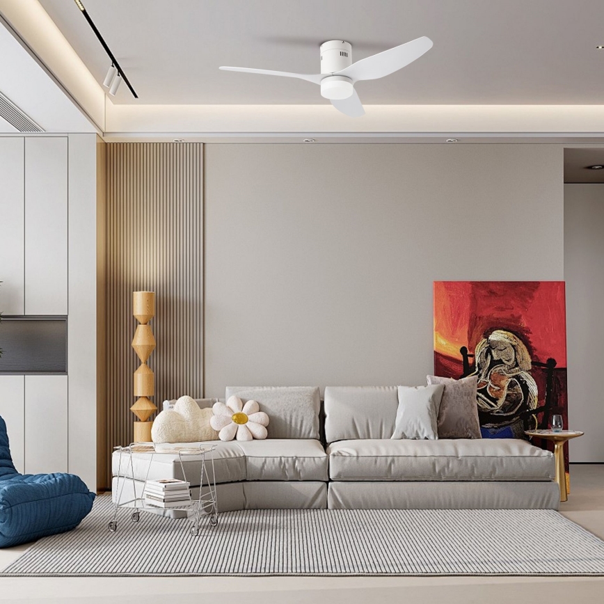 Biely stropný ventilátor sa otáča v moderne zariadenej obývacej izbe s pohovkou, kobercom a abstraktným obrazom.