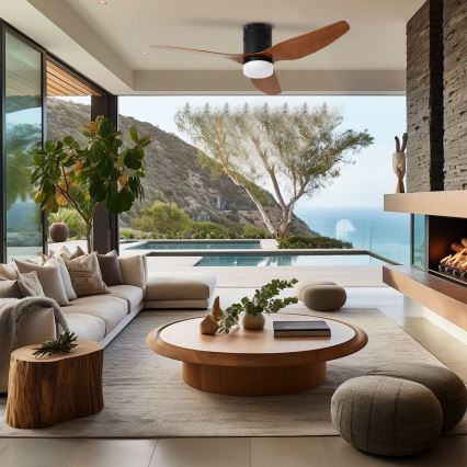 Drevený stropný ventilátor s čiernym telom rotuje v modernom obývacom priestore s výhľadom na bazén a oceán. Nábytok je svetlý, drevený, s neutrálnymi farbami.