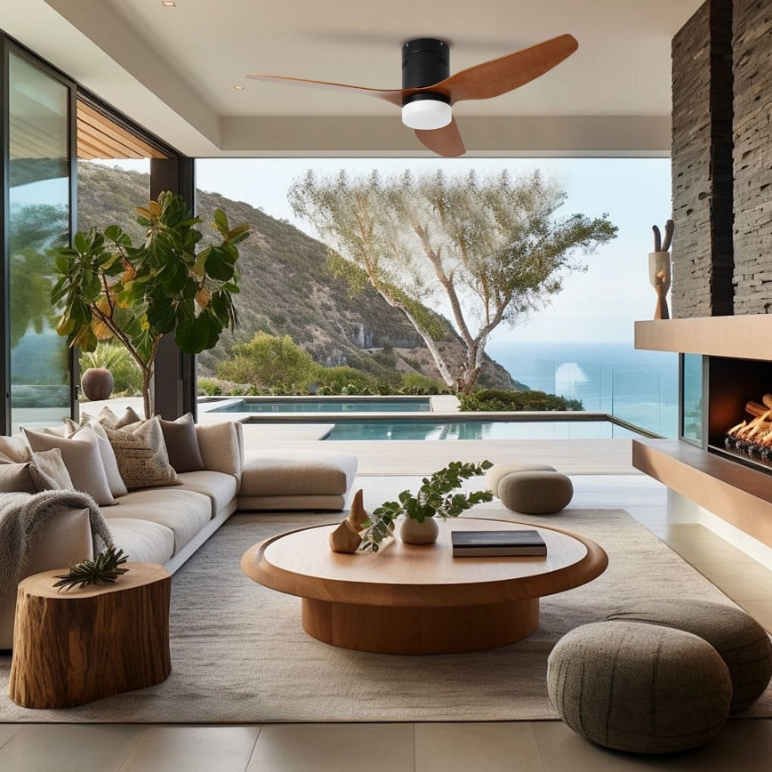 Drevený stropný ventilátor s čiernym telom rotuje v modernom obývacom priestore s výhľadom na bazén a oceán. Nábytok je svetlý, drevený, s neutrálnymi farbami.