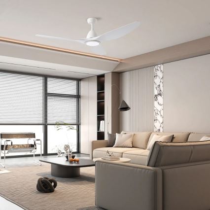 Biely stropný ventilátor s tromi lopatkami sa nachádza v modernej obývacej izbe s rozsiahlym oknom, pohovkou a kávovým stolíkom.