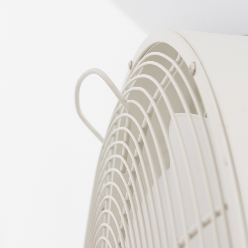 Biely ventilátor s ochrannou mriežkou je pripevnený k stene. Ventilátor má malú, ohnutú kovové držadlo.