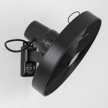 Čierny nástenný ventilátor s lopatami rotuje. Je pripevnený na stenu a má ovládací panel s tlačidlami: ON/OFF, OSC, TIMER, LOW, MED, HIGH.